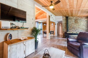 A wooden interior with a television, a fireplace, and a leather chair.