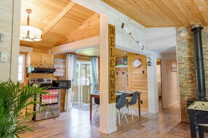 A wooden interior with a kitchen, dining area, and a fireplace. - Sandy's Tiki Hut on Sunset Trail Family Beach Retreat-Steps to Beach (Tiny)