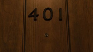 Une porte en bois sur laquelle est gravé le numéro « 401 ».