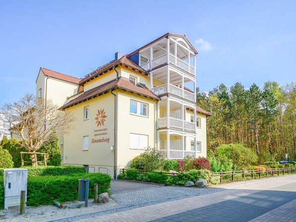 A multi-story building with balconies, a sign indicating it is a vacation rental, and a surrounding landscaped area.