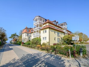 A multi-story building with balconies, a paved walkway, and a sign indicating a private parking area.