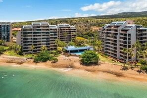 Um hotel à beira-mar com vários edifícios altos, uma piscina e área de praia.