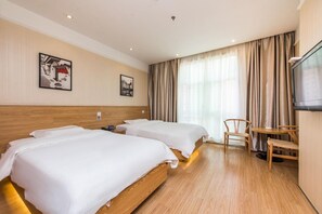 Habitación de hotel con dos camas, televisión, escritorio y una silla.