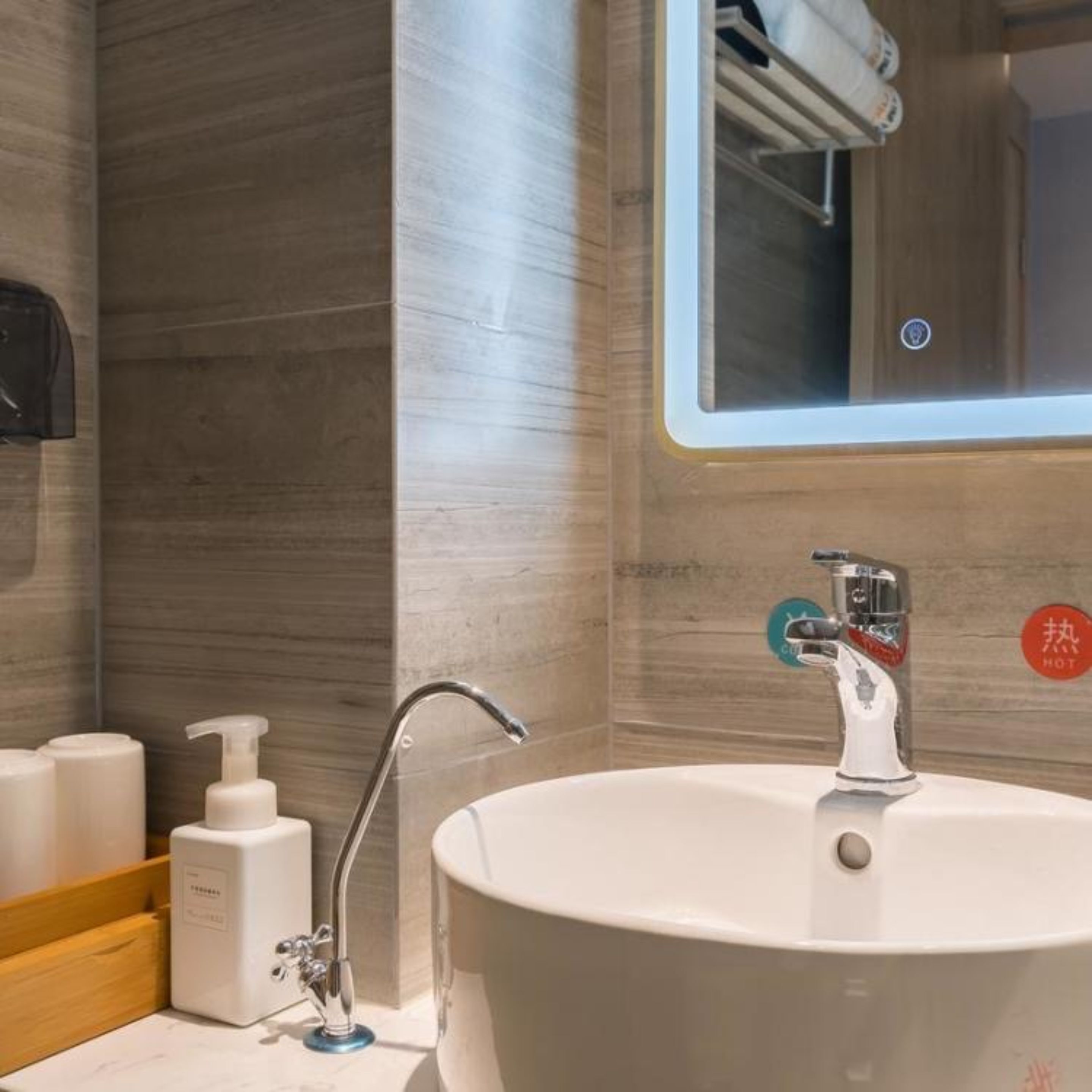 A bathroom with a large sink, a mirror, and a towel rack.