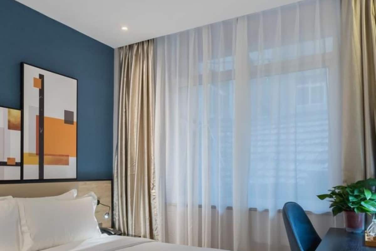 Ein Hotelzimmer mit Bett, Schreibtisch, Stuhl und einer Zimmerpflanze.