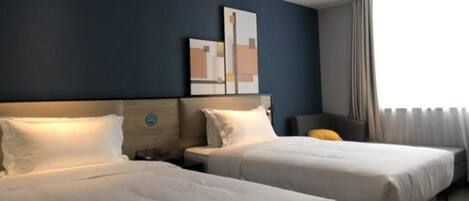 A hotel room with two beds, a nightstand, a wall-mounted artwork, and a window with curtains.