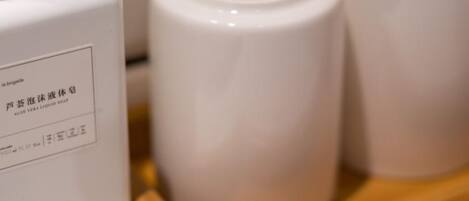 A bottle of liquid soap and two white containers on a wooden surface.