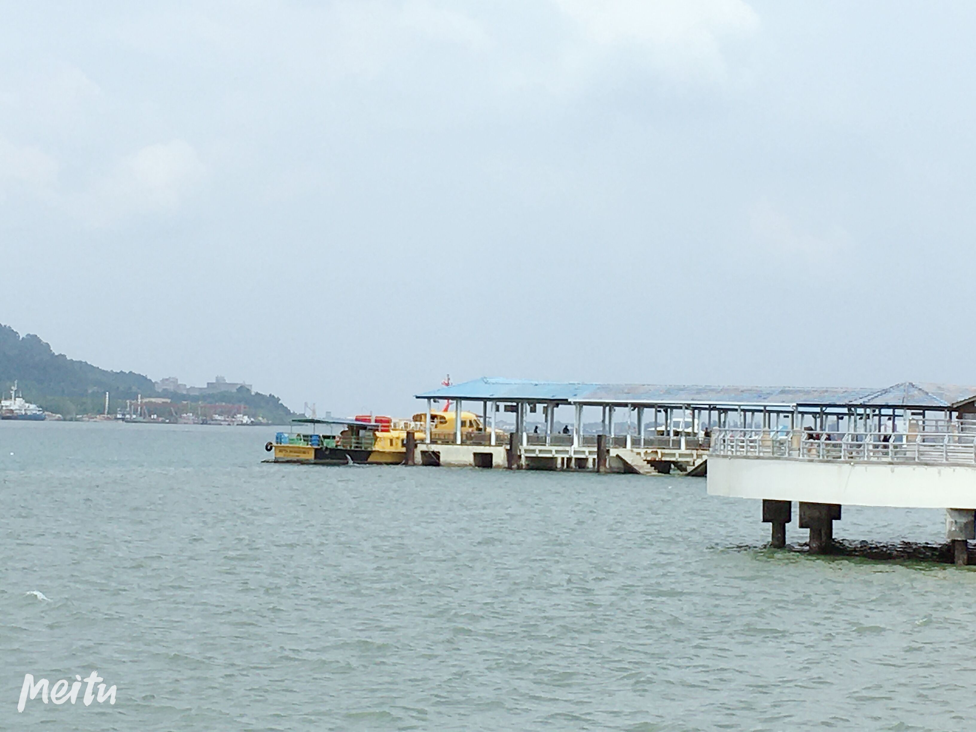 A pier extending into calm water with a covered walkway and a small boat docked nearby.