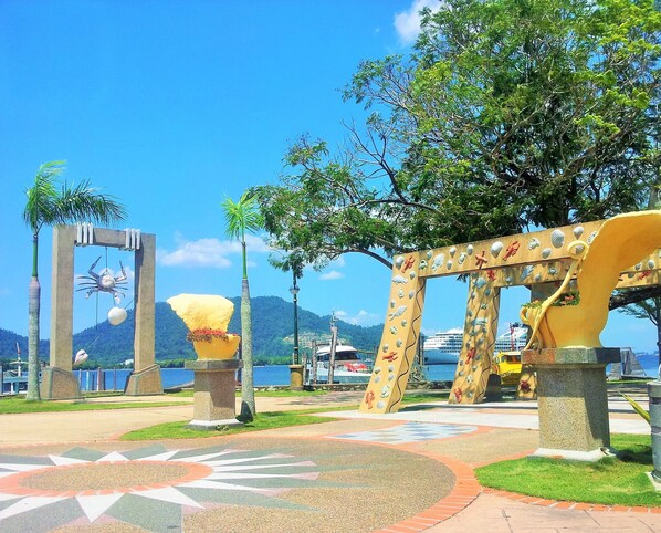 Un parque con esculturas artísticas, un sendero con diseño y vistas al mar.