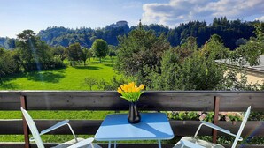 Un tavolo con un vaso di fiori gialli, una panca di legno e vista su un castello su una collina.