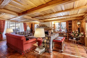 Un salon chaleureux avec une cheminée, un plafond en bois et différents types de sièges.