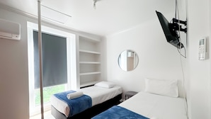 Een moderne hotelkamer met twee bedden, een groot raam, een televisie en een spiegel.
