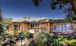Situated amidst lush vegetation, this charming home features a welcoming front porch and a tiled roof.