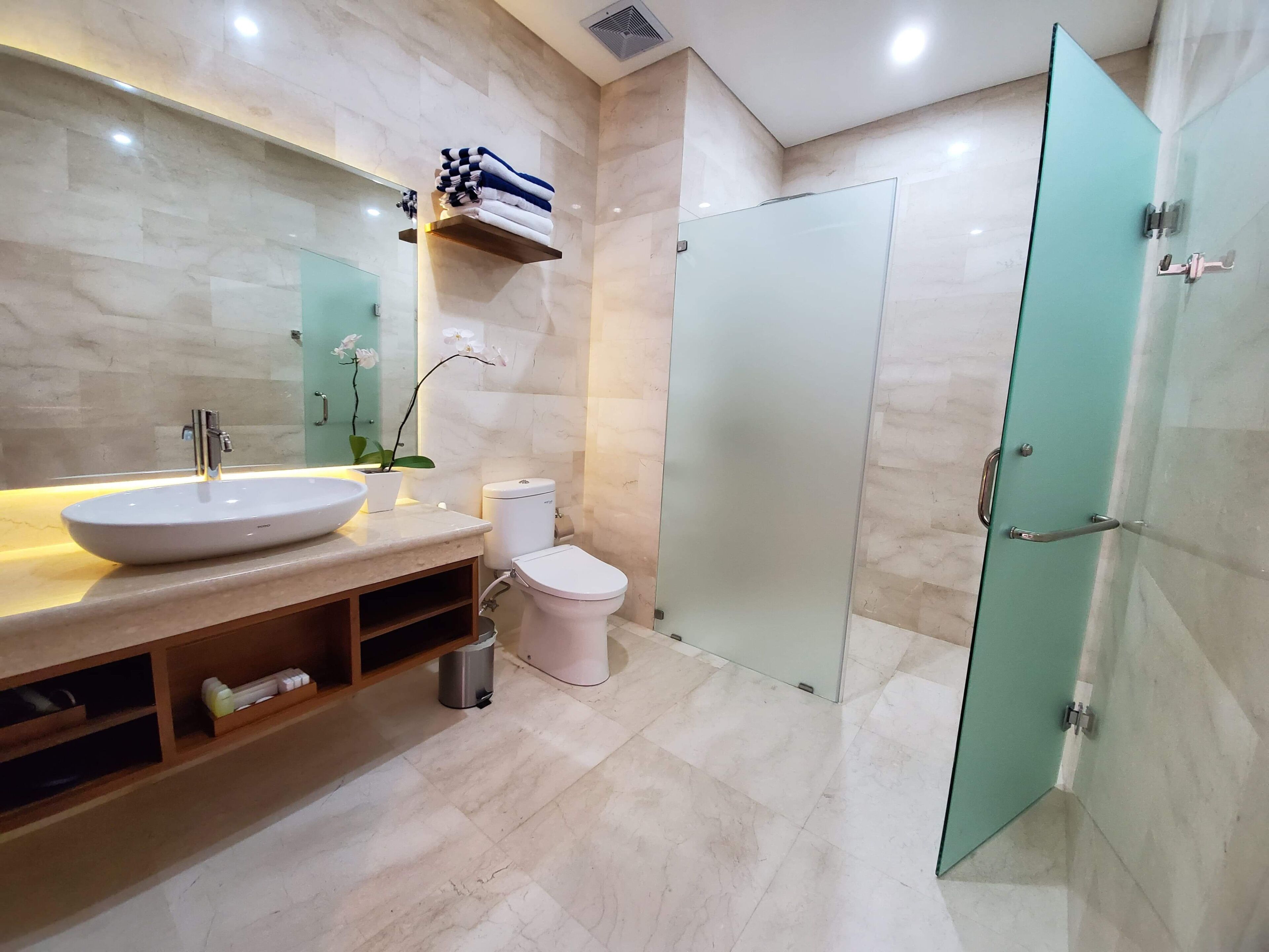 A modern bathroom with a large sink, toilet, and glass shower door.
