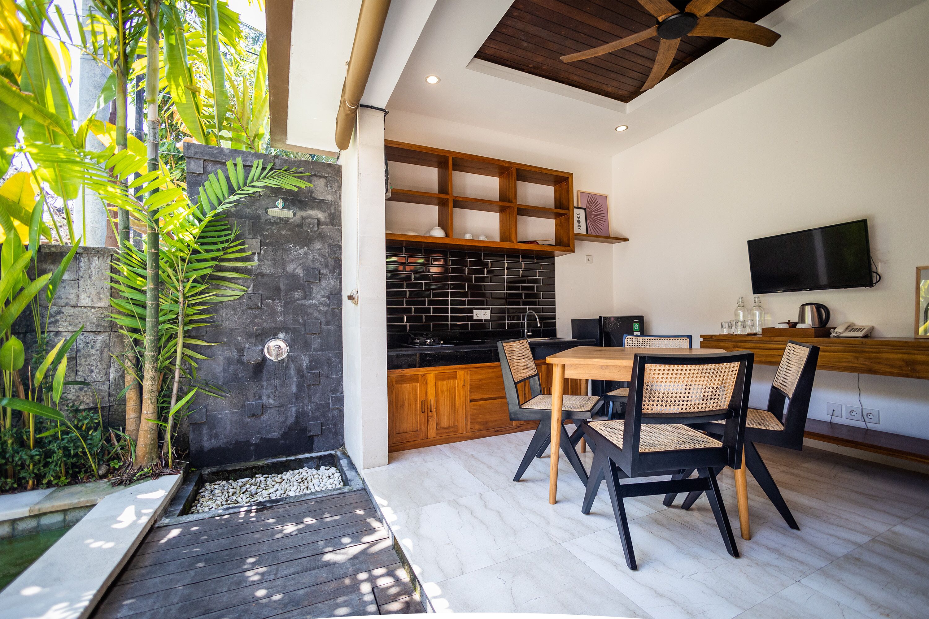A modern kitchen with wooden cabinets, a black backsplash, and a dining area with a table and chairs.