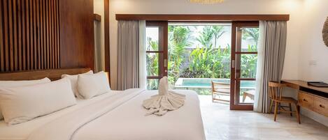 A bedroom with a large bed, a desk, and a view of a swimming pool.