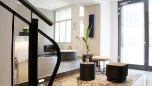 A modern lobby with a glass door, a marble floor, a black round table, and a potted plant. - Hotel im Wigbold Ochtrup (Ochtrup)