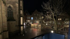 A nighttime view of a town square with a church, a restaurant, and a tree. - Hotel im Wigbold Ochtrup (Ochtrup)