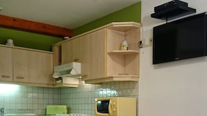 A compact kitchen with wooden cabinets, a microwave, a small oven, and a dining table with chairs. - Apartment 1: Apartment in private property with quiet courtyard (Bergheim)