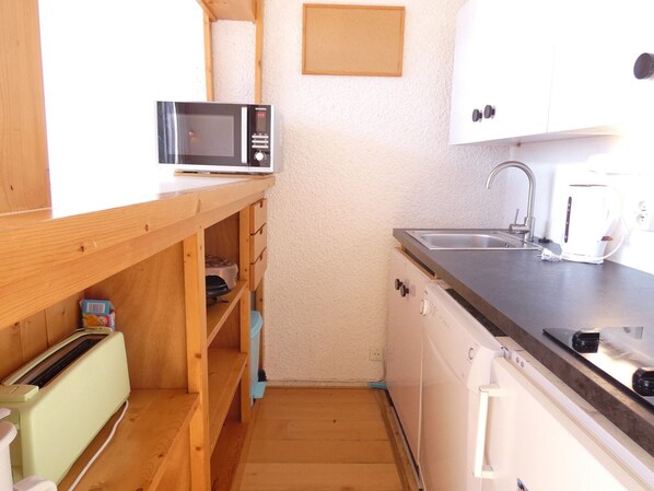 A compact kitchen with a microwave, toaster, sink, and dishwasher.