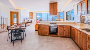 A modern kitchen with wooden cabinets, a central island, and a dining area with a table and chairs.