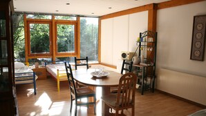 A cozy room with a wooden dining table, chairs, and a window overlooking a forest.
