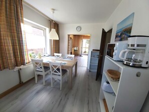 Una cocina compacta con zona de comedor, una cafetera y un reloj en la pared.