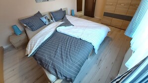 Une chambre à coucher comprenant un lit, une armoire, une table de chevet et une étagère fixée au mur.
