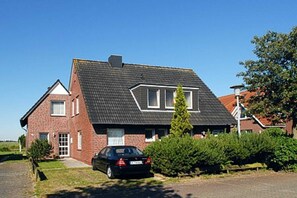 Ein zweistöckiges Haus mit geneigtem Dach, einem Auto auf der Auffahrt und einem gepflegten Rasen.