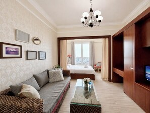 A hotel room with a sofa, a glass coffee table, a bed, a TV, and a city view through the window. - The Soulmate - Cozy studio central HCM  with  Rooftop Pool (Ho Chi Minh)