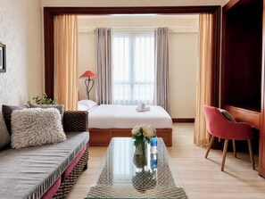 A hotel room with a bed, a sofa, a glass coffee table, a chair, and a window with curtains. - The Soulmate - Cozy studio central HCM  with  Rooftop Pool (Ho Chi Minh)