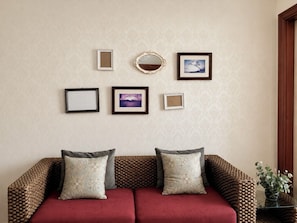 Una habitación con sofá, dos cojines y cuatro cuadros en la pared.
