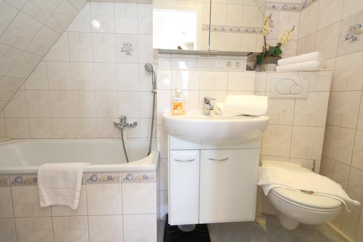Ein Badezimmer mit Badewanne, Waschbecken und Toilette, alles in Weiß.