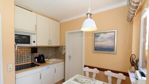 A compact kitchen with a microwave, coffee maker, and a dining table with chairs.