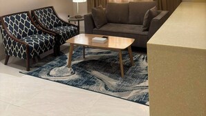Een woonkamer met een bank, twee fauteuils, een bijzettafeltje en een kamerkleed met een patroon.