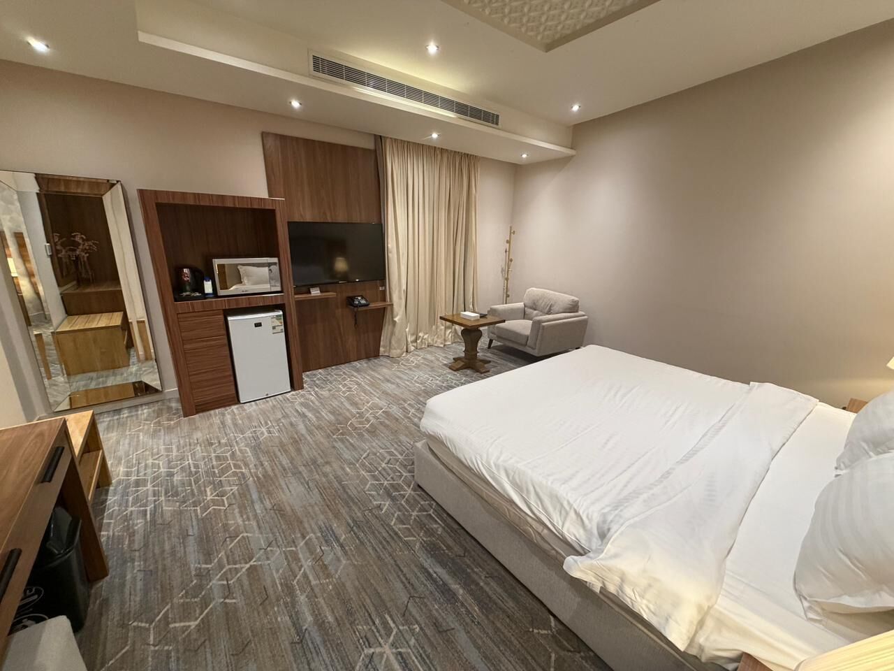 A hotel room with a bed, a desk, a television, and a wardrobe.