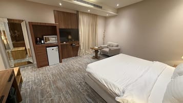 A hotel room with a bed, a desk, a television, and a wardrobe.