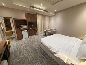 A hotel room with a bed, a desk, a television, and a wardrobe. - Shorfa Loft Hotel (Riyadh)