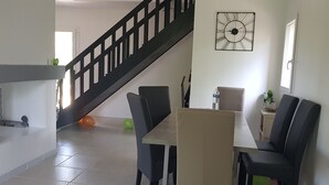 A room with a staircase, a dining table with chairs, a clock on the wall, and a window. - Beautiful Villa in Green Provence with Swimming Pool and Bowling Alley (Tourves)