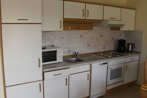 A kitchen with white cabinets, a microwave, a sink, a coffee maker, and a dishwasher.