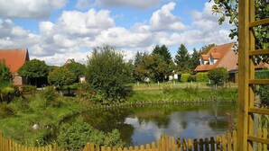 A pond surrounded by a wooden fence, with houses in the background. - Apartment Schneider (Wittmund)