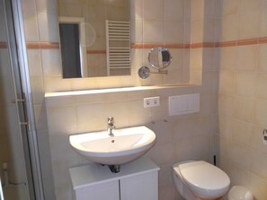 Un baño con lavabo, inodoro, espejo y toallero.