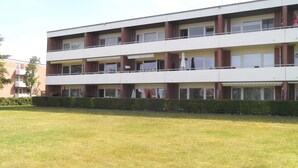 Un edificio a più piani con tetto piatto, finestre rettangolari e un balcone al piano superiore.