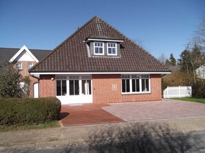 A two-story house with a pitched roof, a front porch, and a driveway. - Apple blossom house, Schmalstieg 1 (Wyk auf Föhr)