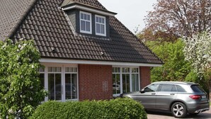 A house with a sloped roof, a brick facade, and a car parked in the driveway. - Apple blossom house, Schmalstieg 1 (Wyk auf Föhr)