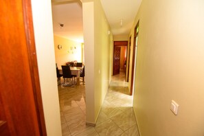 Um corredor com área de jantar, cozinha e uma porta que dá para outro quarto.