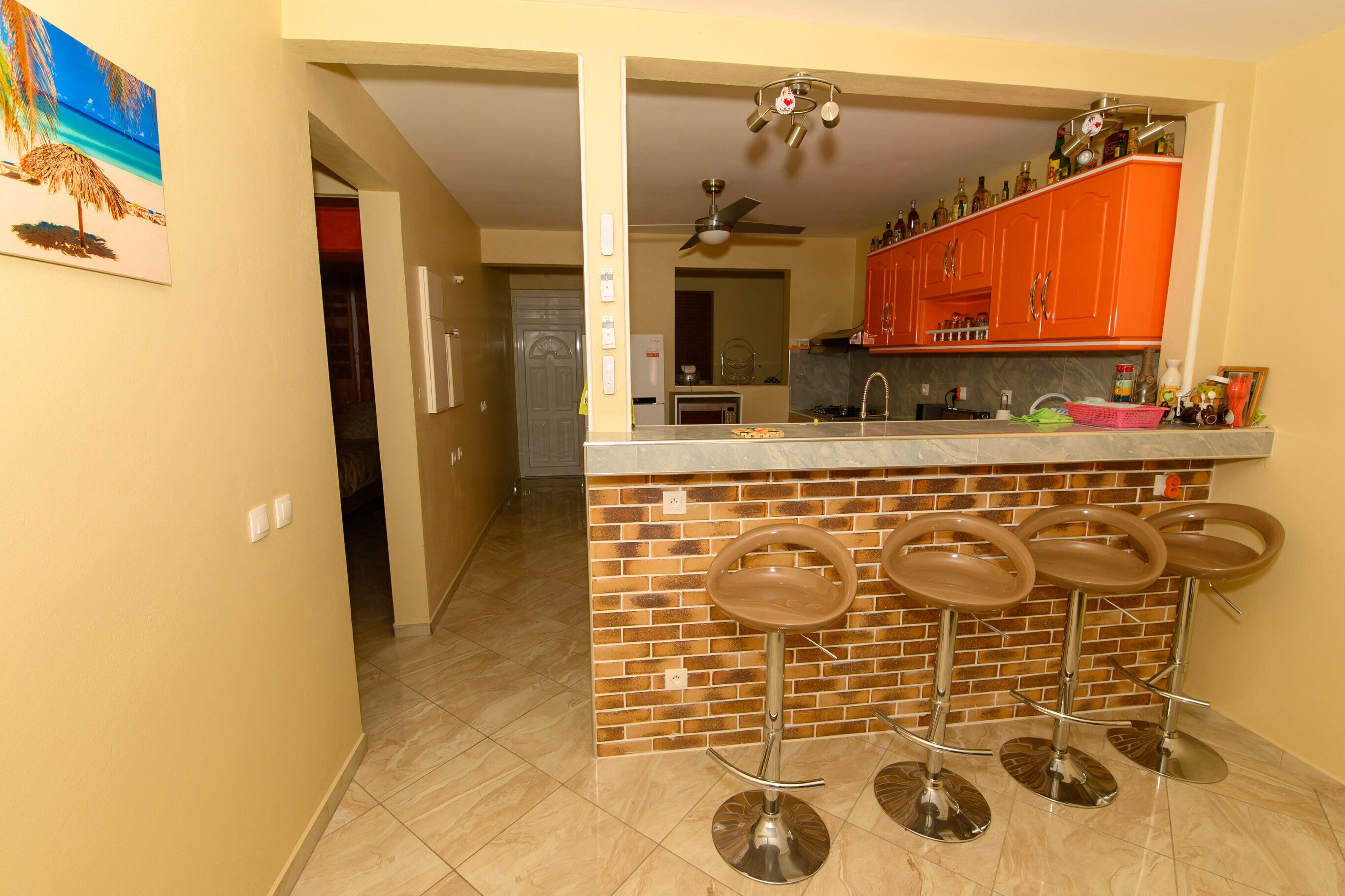 A kitchen with a bar area, a ceiling fan, and a refrigerator.