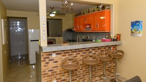 Eine Küche mit Backsteinwand, einer Bar mit Hockern und einem Kühlschrank.