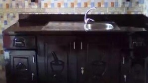 A kitchen with dark cabinets, a tiled backsplash, and a stainless steel sink. - Hakaba (Conakry)