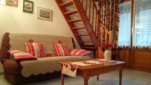 Uma sala de estar aconchegante com um sofá marrom, almofadas listradas, uma mesa de centro de madeira e uma escada.